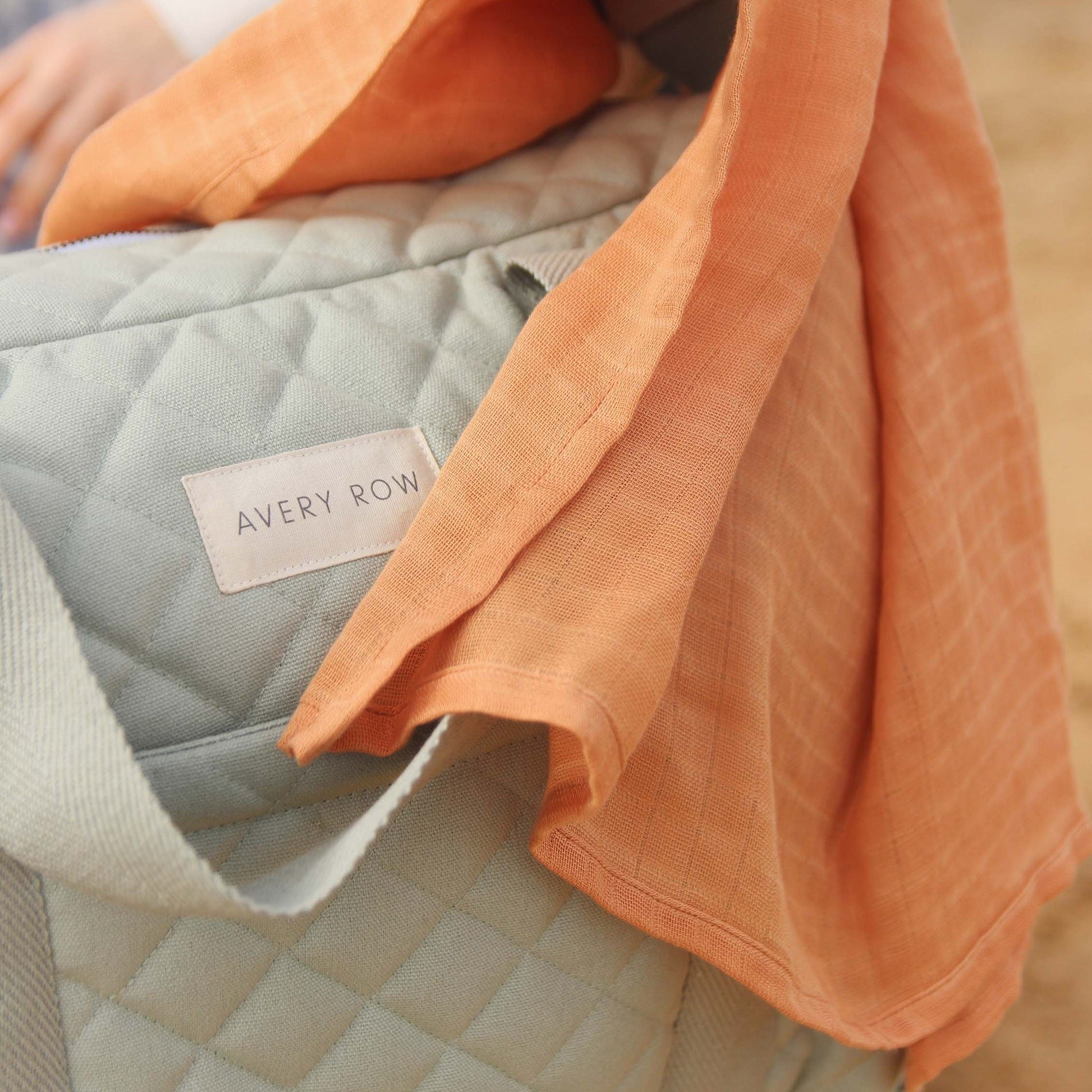 Close-up of a quilt with a visible 'Avery Row' label, featuring soft textures and colors.