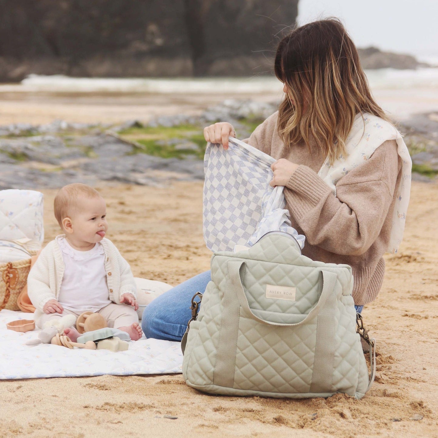 Woman and baby on a beach with a quilted bag