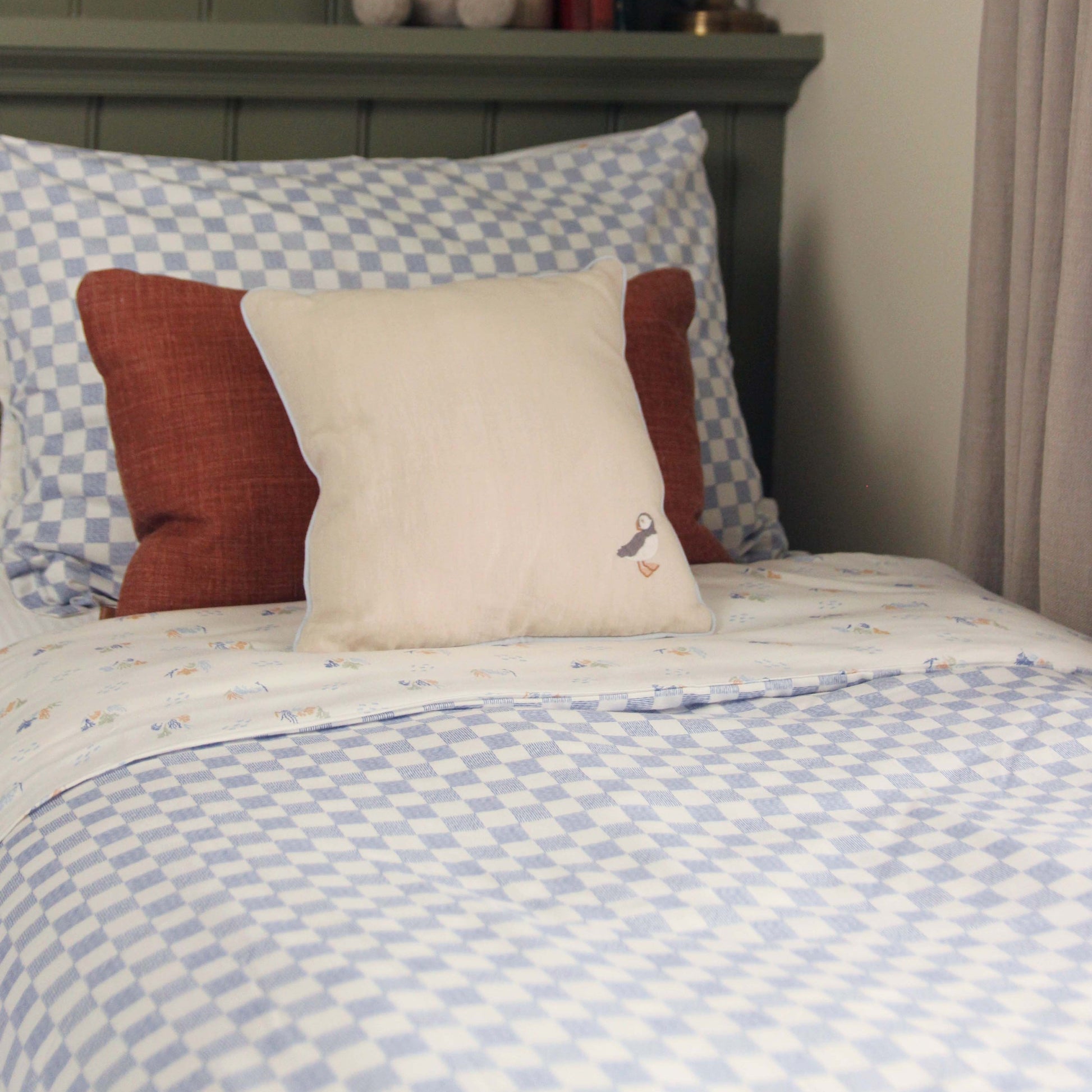 Bed with checkered bedding and patterned pillows in a bedroom setting