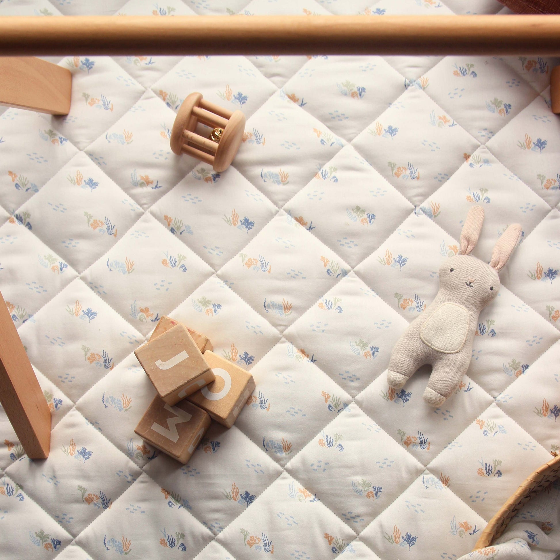 Baby play mat with toys and blocks on a quilted surface