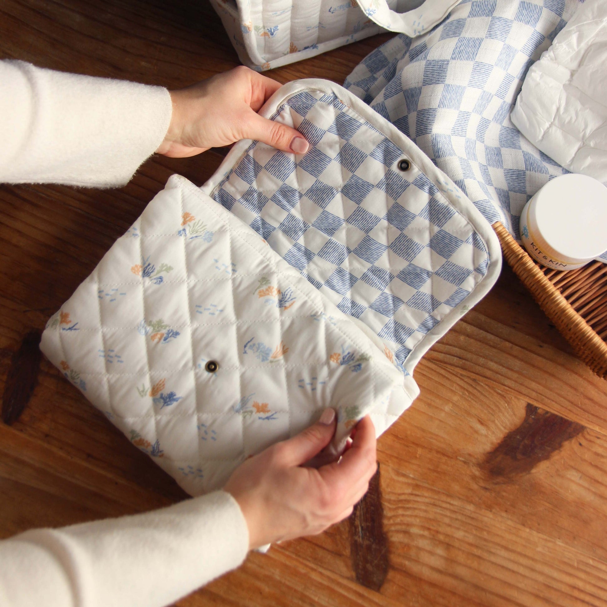 Person holding a quilt with blue and white checkered pattern on a wooden floor.