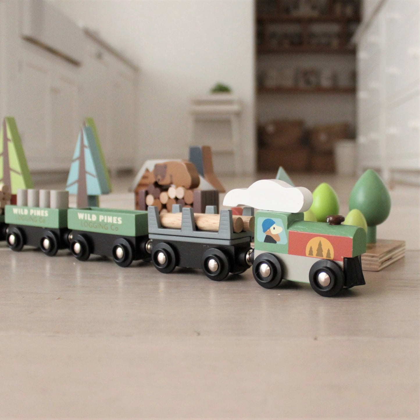 Wooden toy train set on a wooden floor with a blurred indoor background