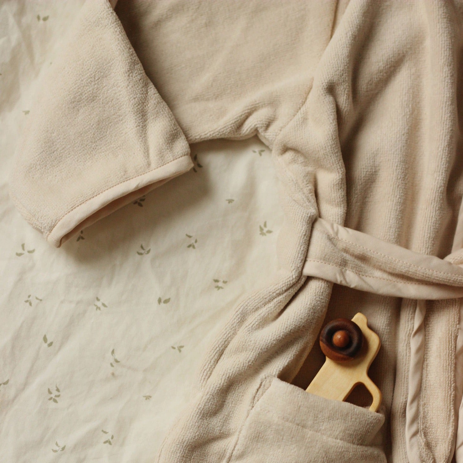 Beige robe with a wooden toy on a textured surface