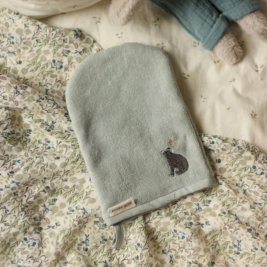 Green fleece mitt with bear design on a floral blanket