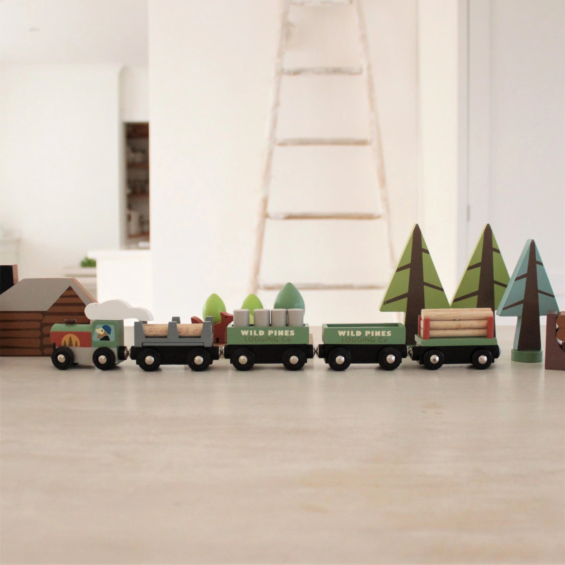 Wooden toy train set with trees on a wooden floor
