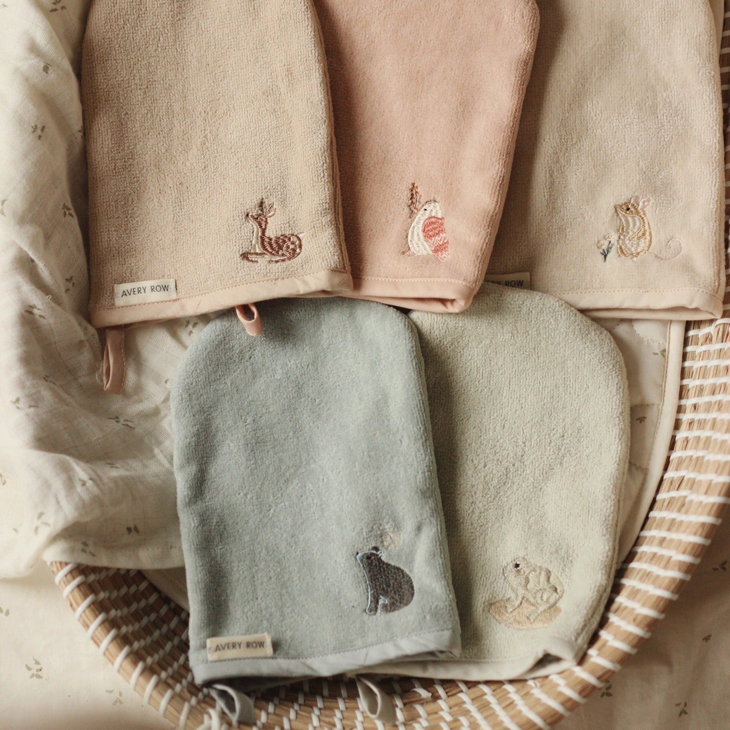 Set of folded towels with embroidered designs on a woven basket