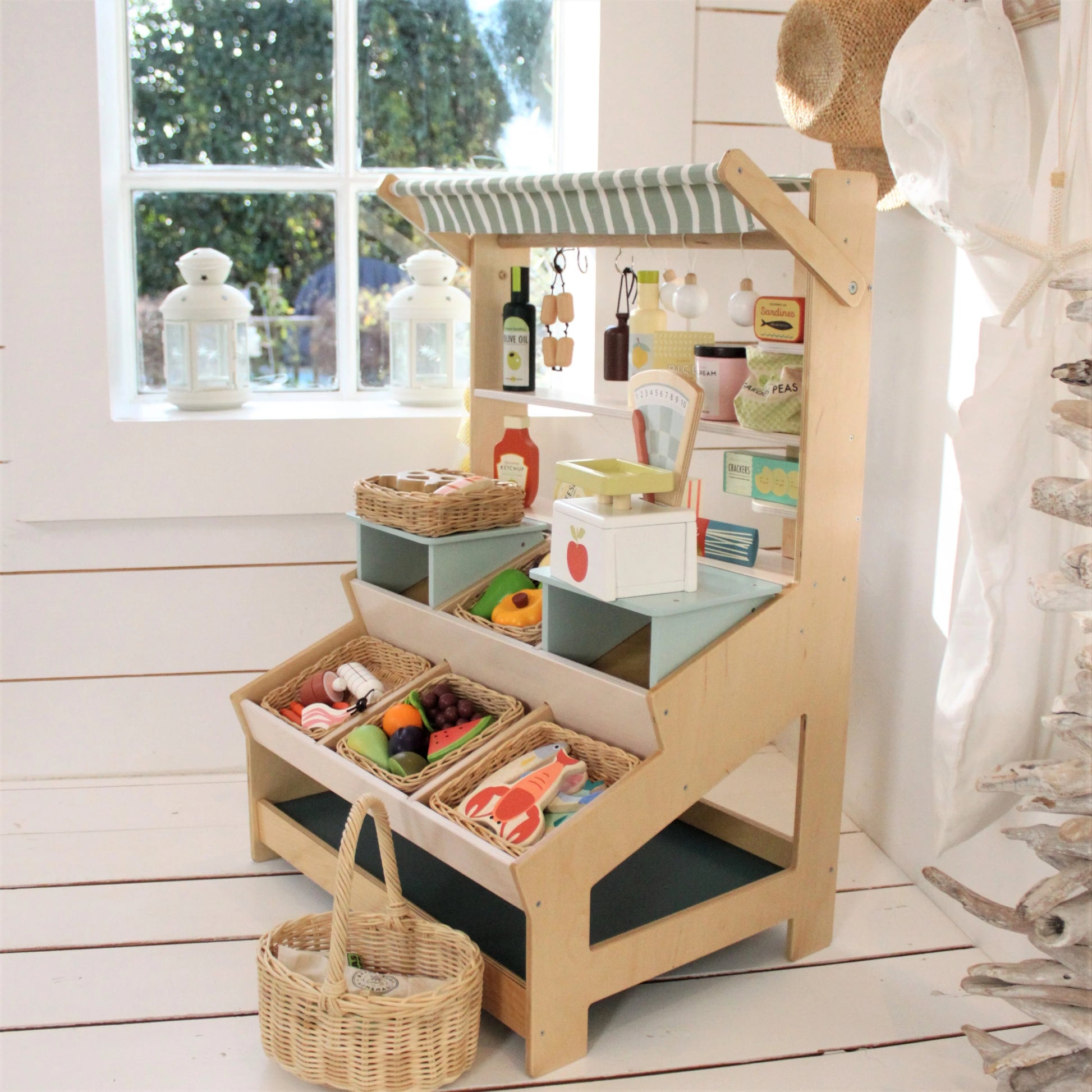 Children's play kitchen set with various toys and items on a wooden floor.
