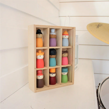 Set of colorful wooden dolls in a wooden display box on a light wooden floor.