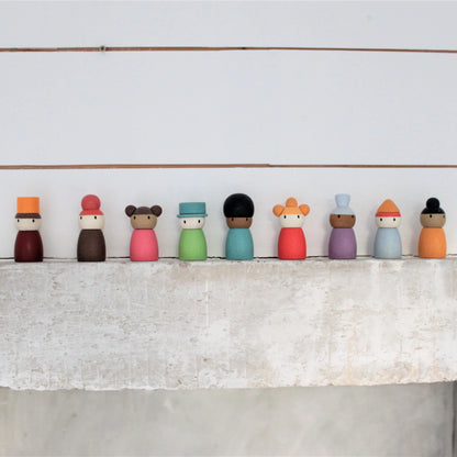 Row of colorful wooden peg dolls on a white surface with a light gray background