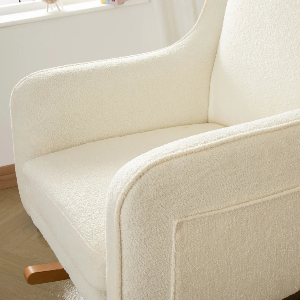 Close-up of a beige armchair with wooden legs in a room.