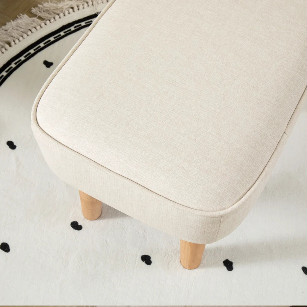 Beige stool with wooden legs on a white rug with black heart patterns