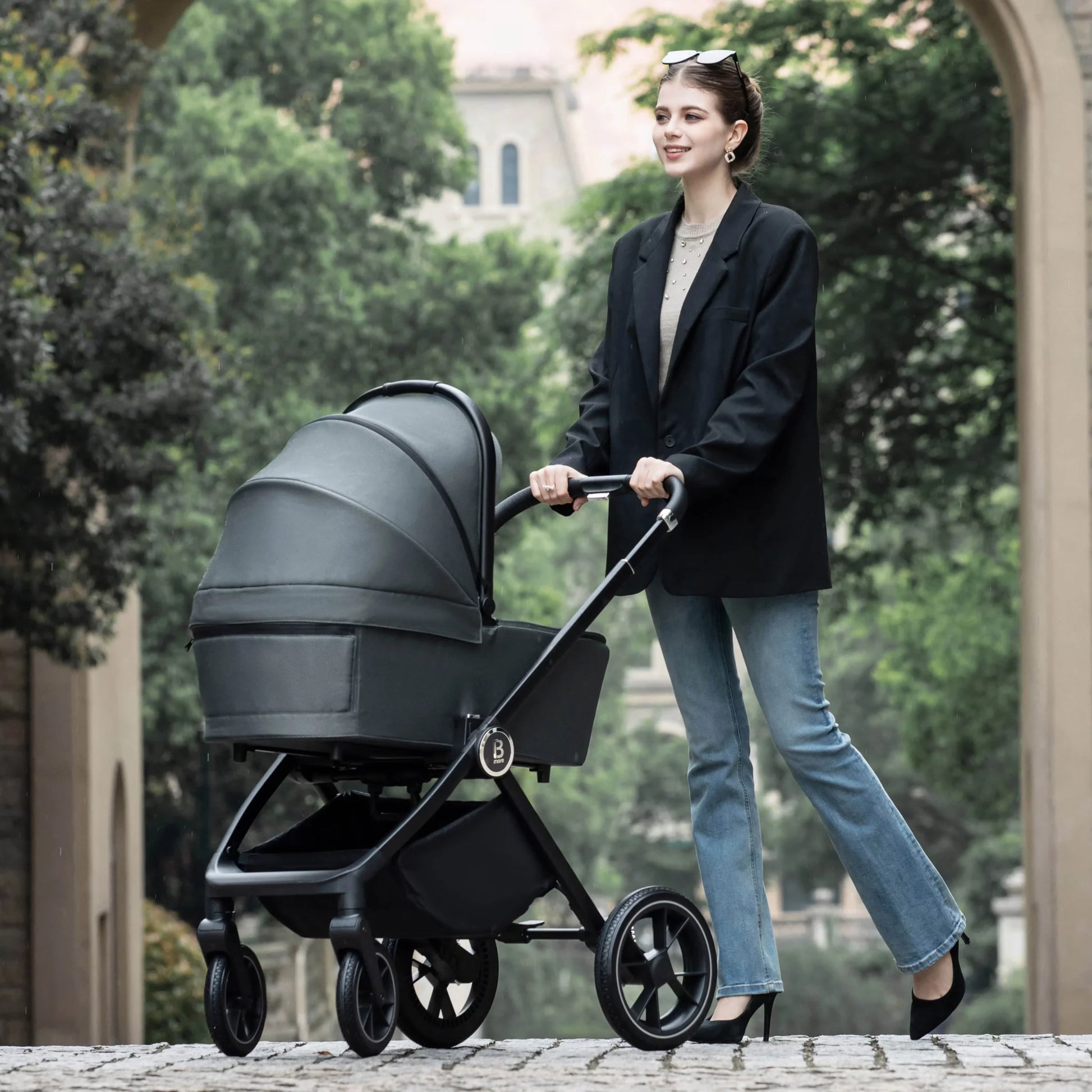 Woman pushing a stroller in an outdoor setting with trees and buildings in the background