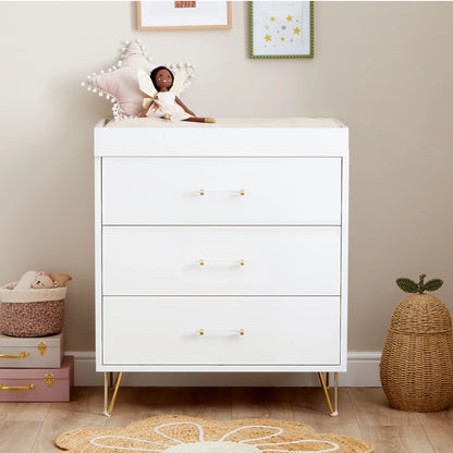 White dresser with gold legs in a room setting with toys and decor.
