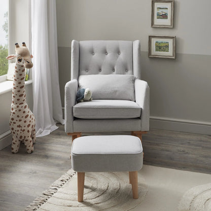 Gray upholstered rocking chair with ottoman in a nursery setting