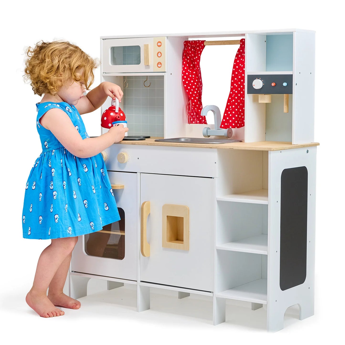 Child playing with a toy kitchen set on a white background