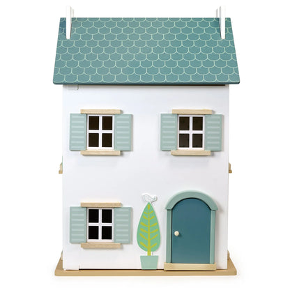 Small model house with a green roof and door on a white background