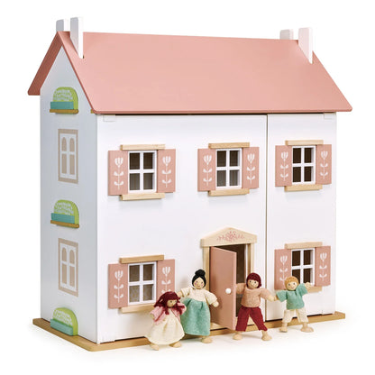 Dollhouse with pink roof and four dolls in front on a white background