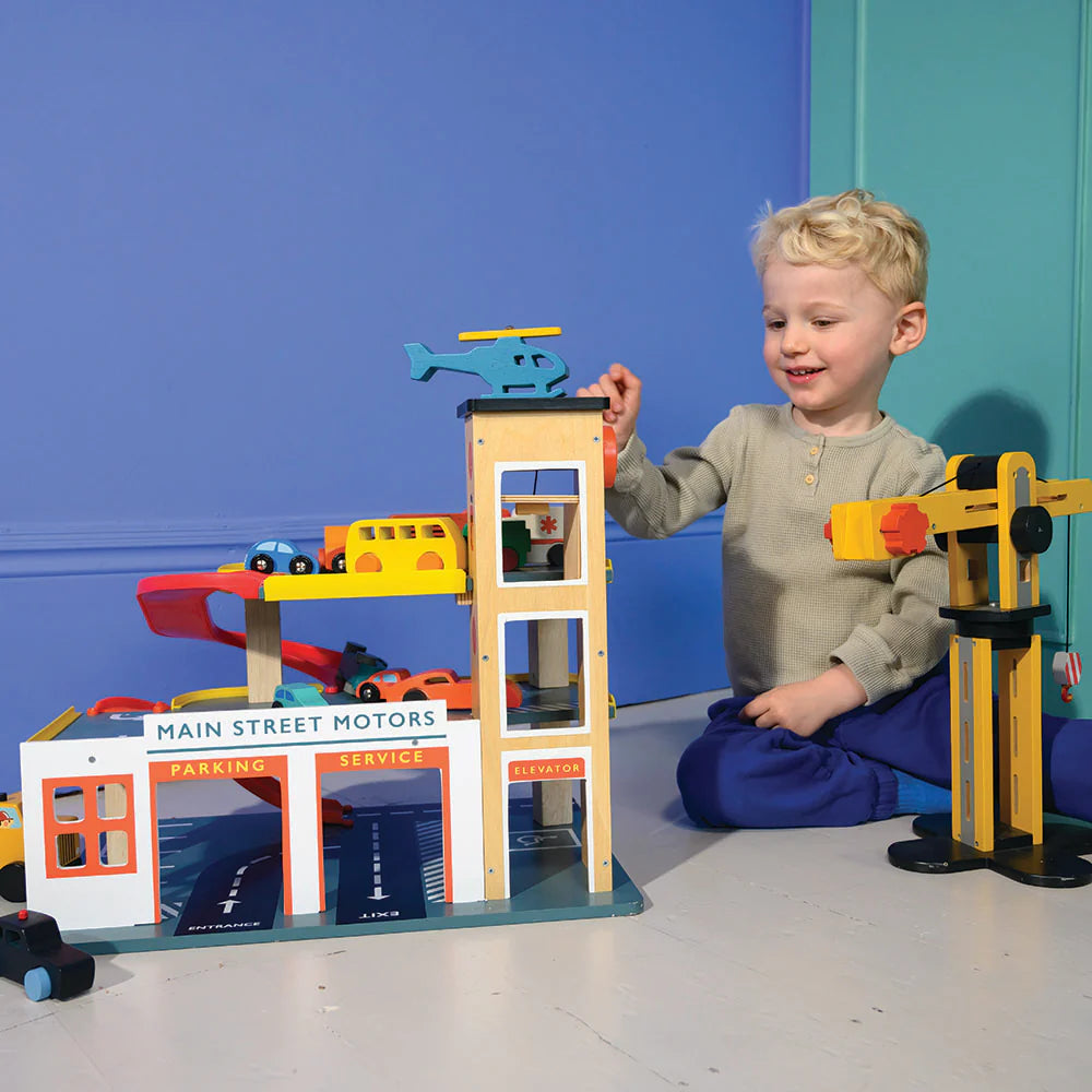 Child playing with a toy garage set against a blue wall