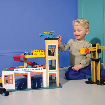 Child playing with a toy garage set against a blue wall