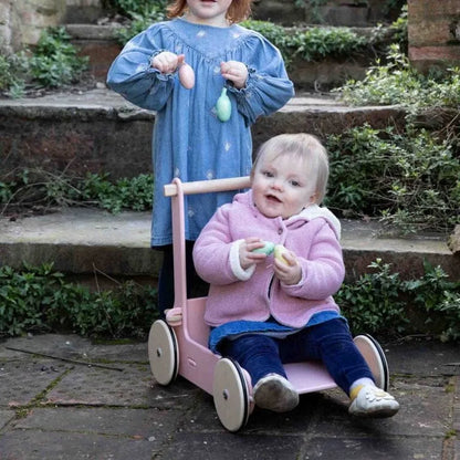 Two children playing with a pink scooter on stone steps.