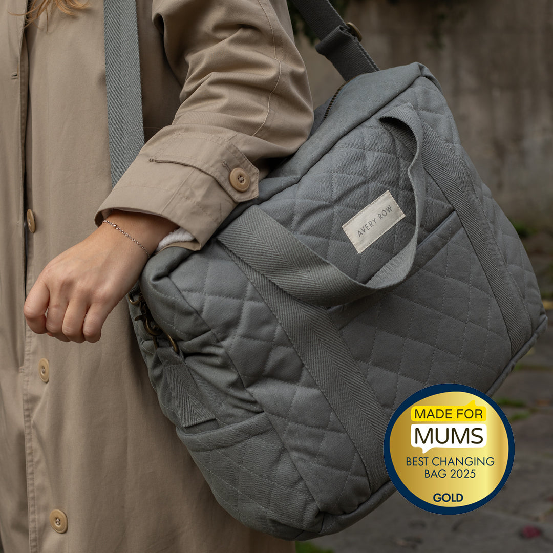 Gray quilted changing bag held by a person, with a 'Made for Mums' award badge.