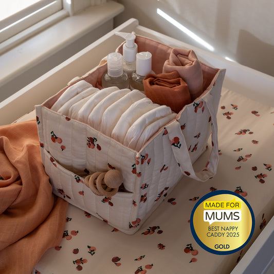 Nappy caddy with baby items on a changing table, featuring a 'Made for Mums' award badge.