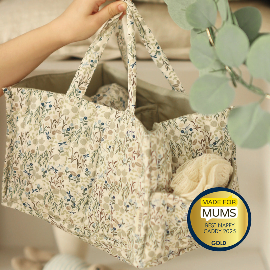 Floral-patterned nappy caddy held by a hand with a 'Made for Mums' award badge.