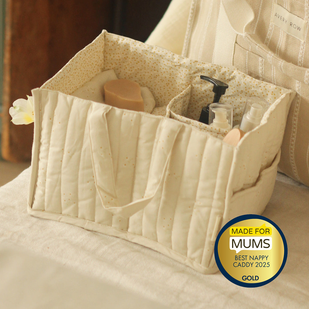 Beige quilted caddy with baby products on a bed, featuring a 'Made for Mums' award badge.