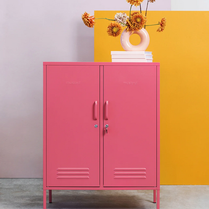 Pink cabinet with a vase of flowers against a colorful wall