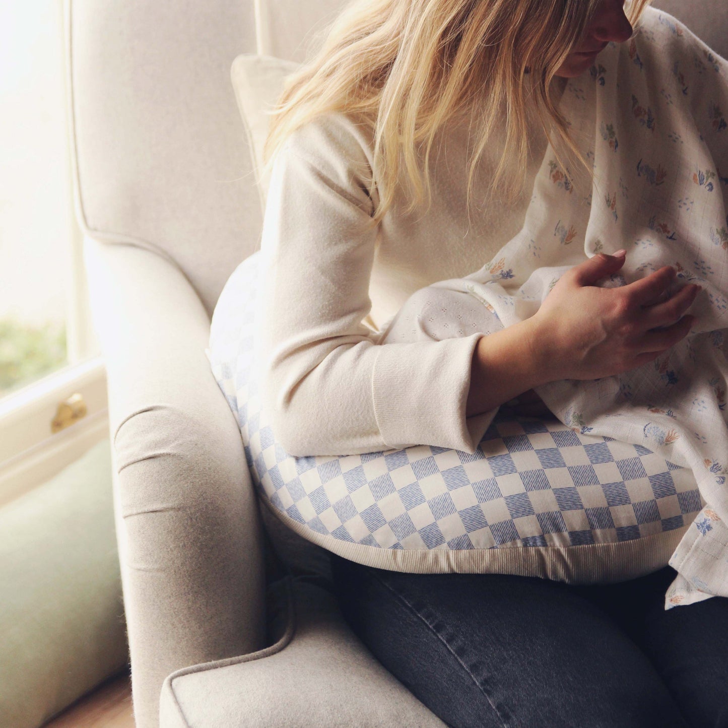 Woman sitting on a couch with a checkered pillow and blanket