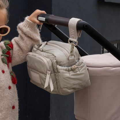Beige quilted bag attached to a stroller handle