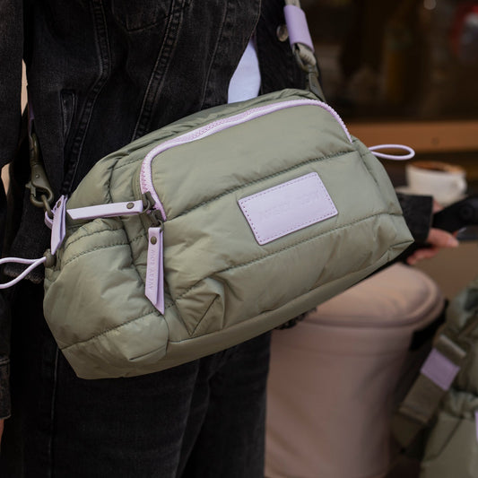 Green puffer bag worn by a person with a blurred background