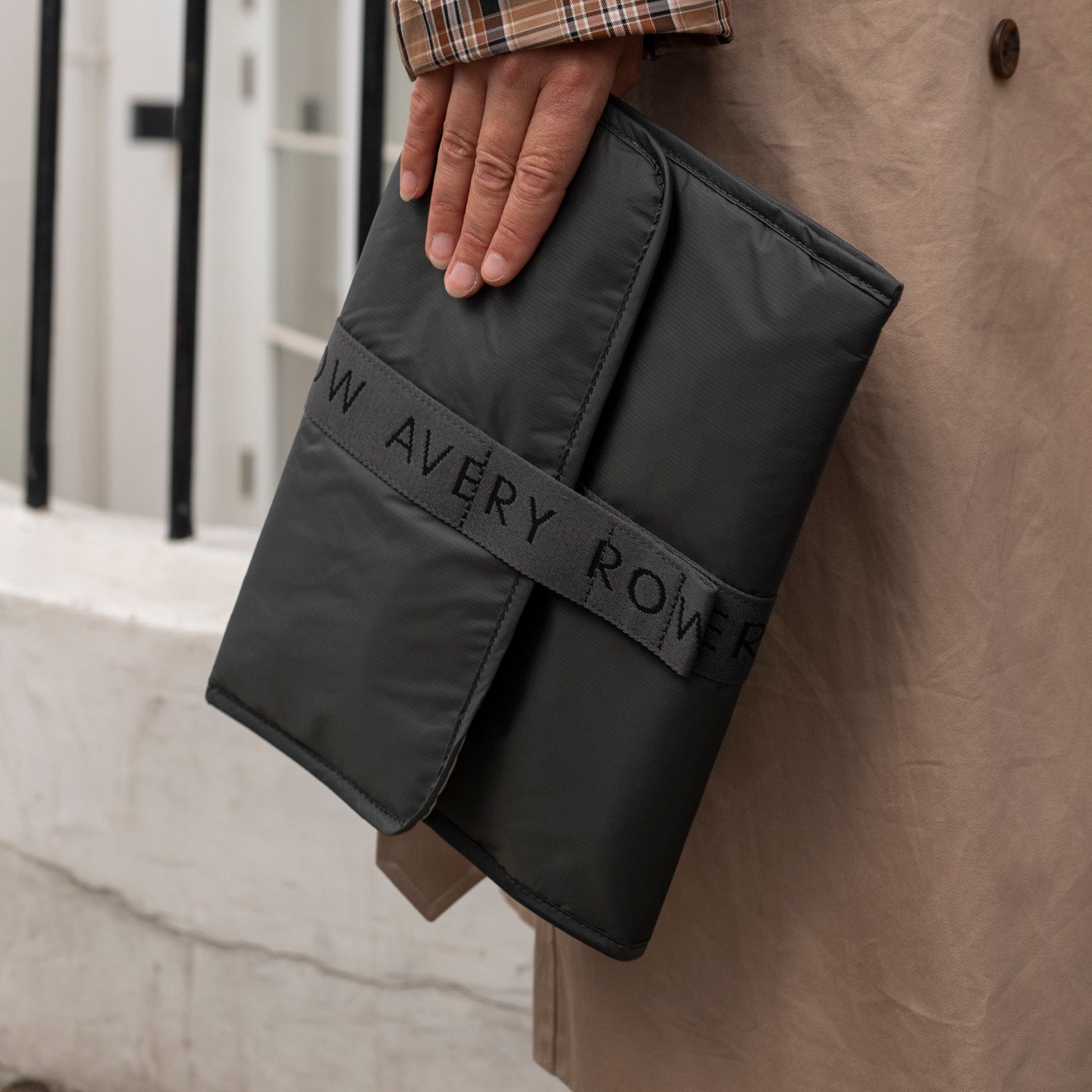 Black fabric roll with 'W Avery Rover' branding held by a person against a beige wall.