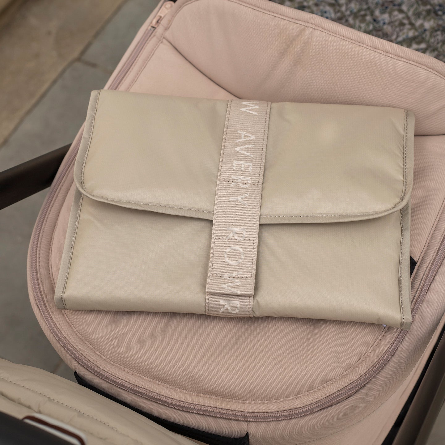 Beige pouch with 'New Avery Row' branding on a pink suitcase.