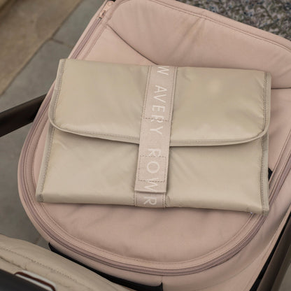 Beige pouch with 'New Avery Row' branding on a pink suitcase.