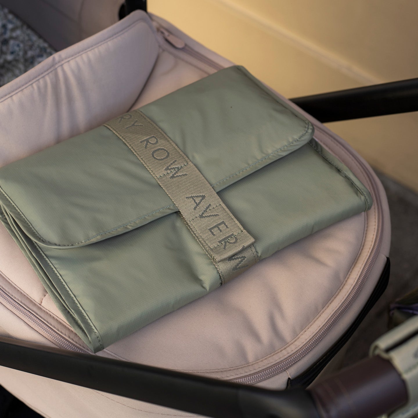 Folded green blanket with 'Row Avera' branding inside a suitcase.