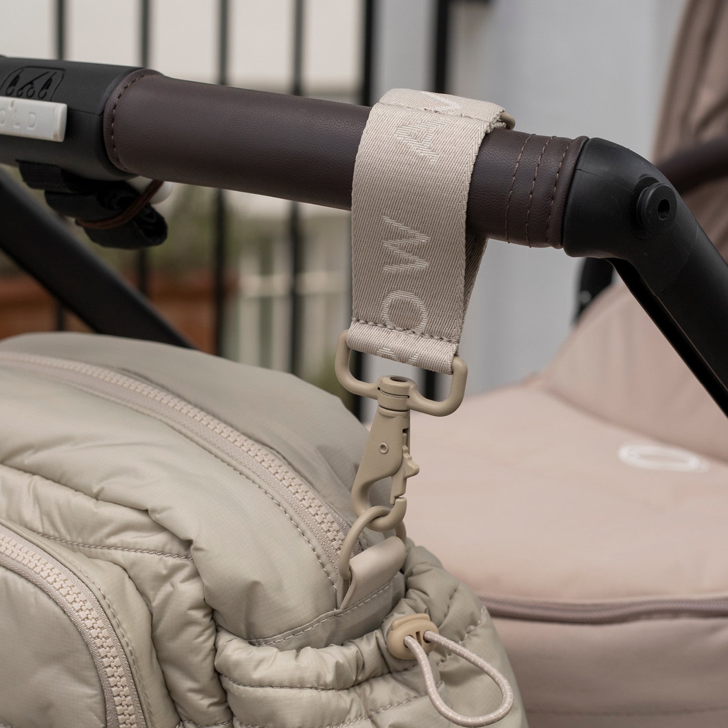 Close-up of a stroller handle with a strap, showing brand 'MamaWoo'.