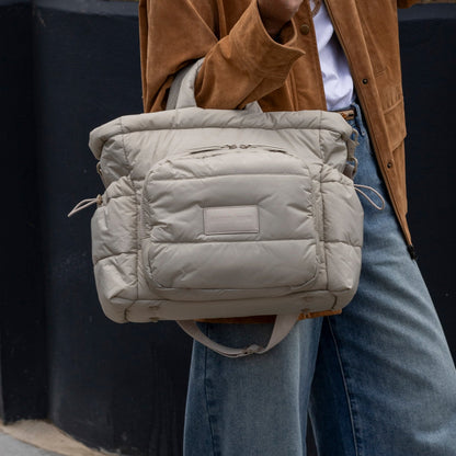 Person wearing a beige quilted backpack with a dark background
