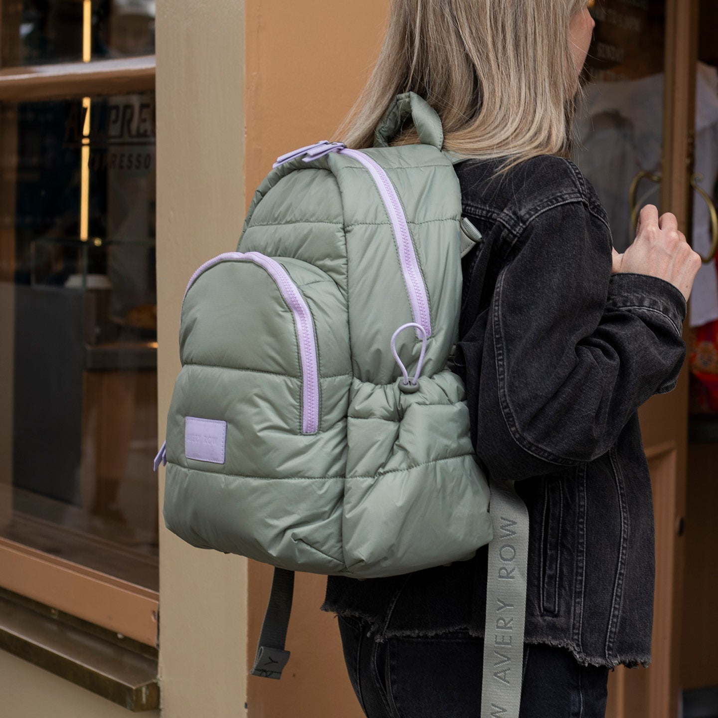 Person wearing a green puffer backpack with pink accents indoors.