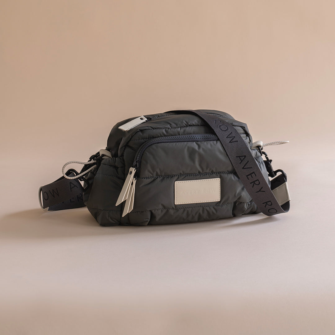Black waist bag with a visible brand label on a beige background