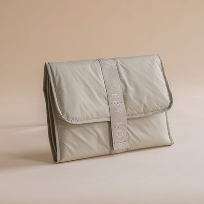 Folded beige pouch with a strap on a beige background