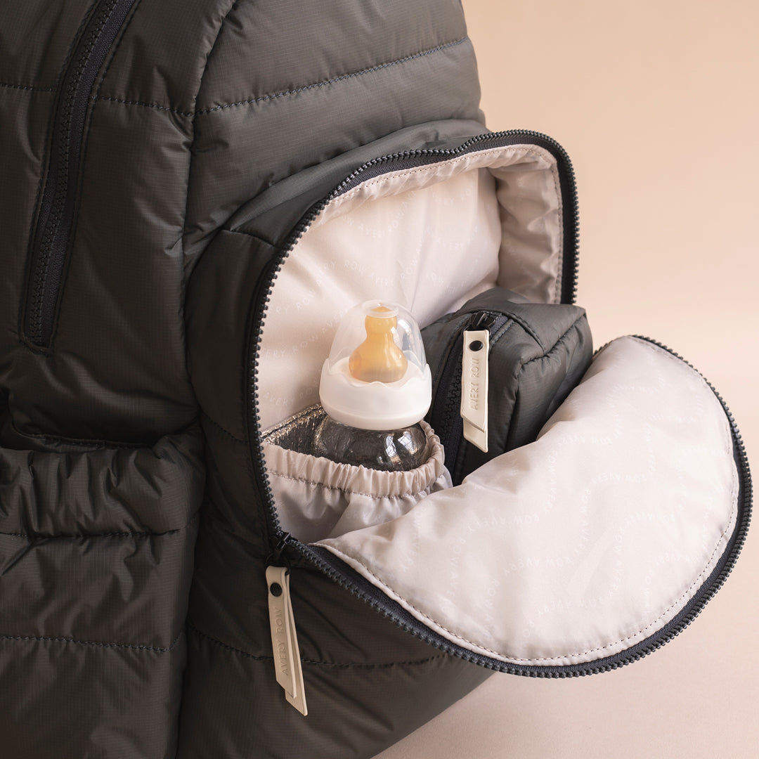 Pacifier inside a black puffer jacket pocket with beige background