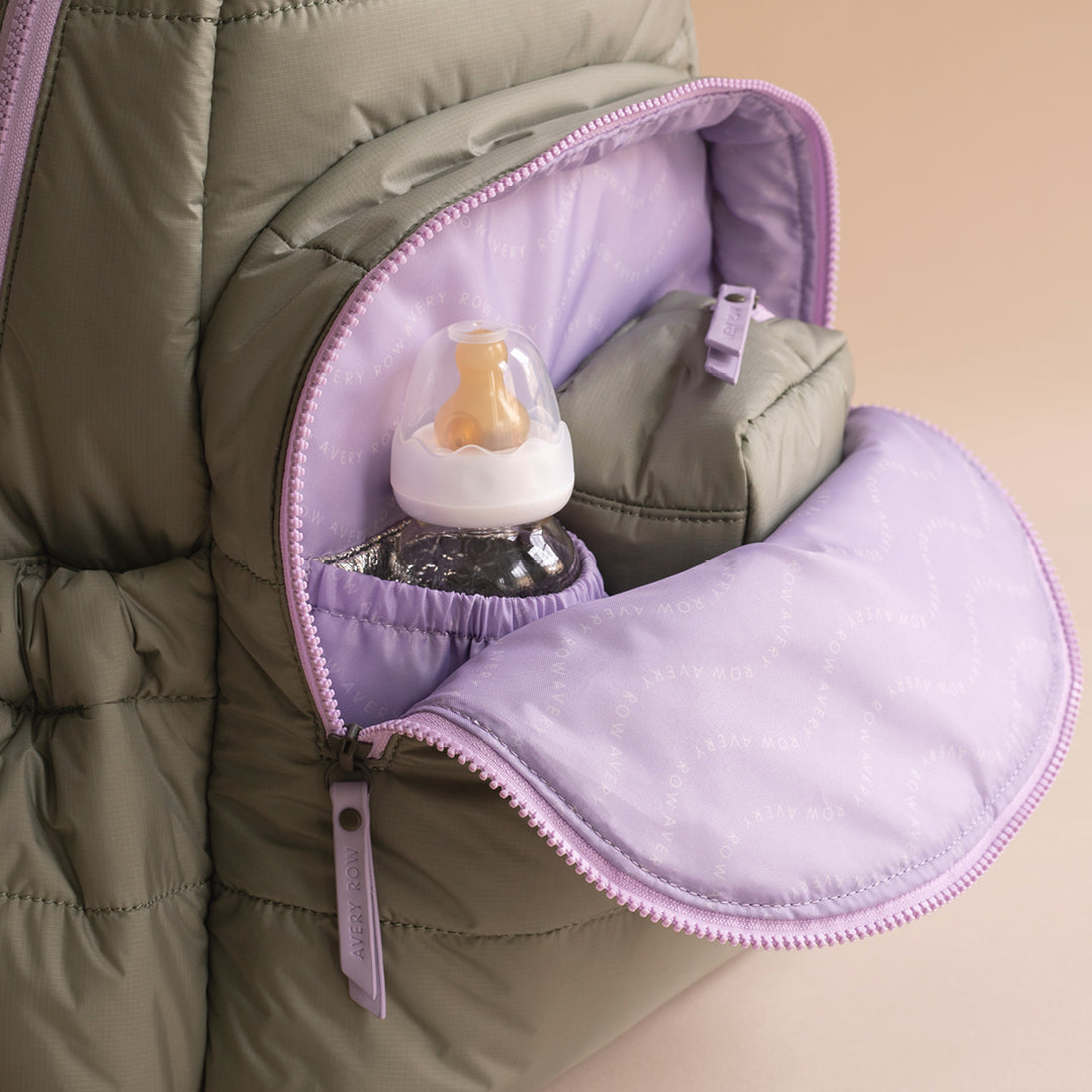Baby bottle inside a green puffer jacket with purple interior
