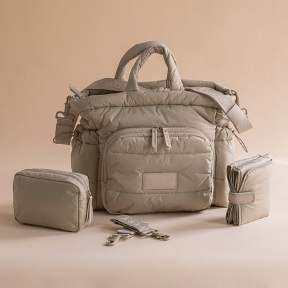 Beige diaper bag with accessories on a beige background