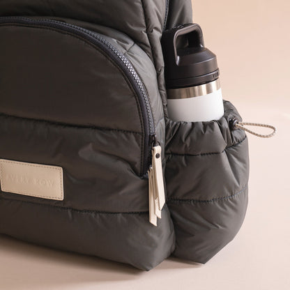 Black backpack with a water bottle attached on a beige background