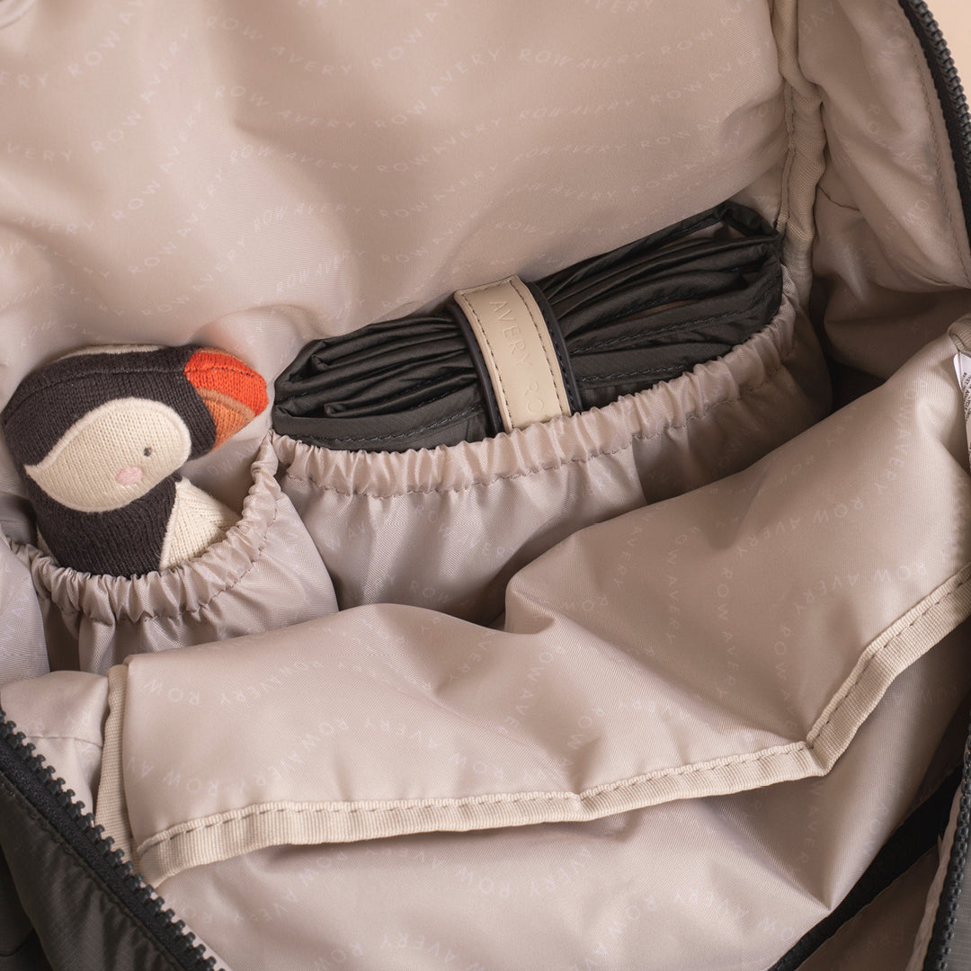 Close-up of a beige bag with a plush toy and rolled-up black fabric inside.
