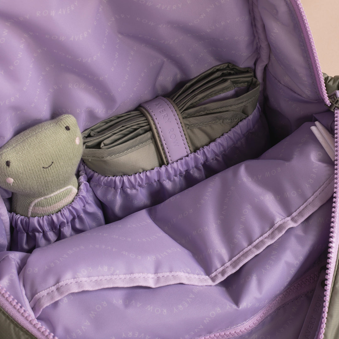 Purple fabric with a green plush toy and folded green blanket inside