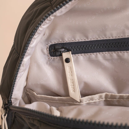 Close-up of a backpack zipper with 'Every Row' brand tag on beige fabric.