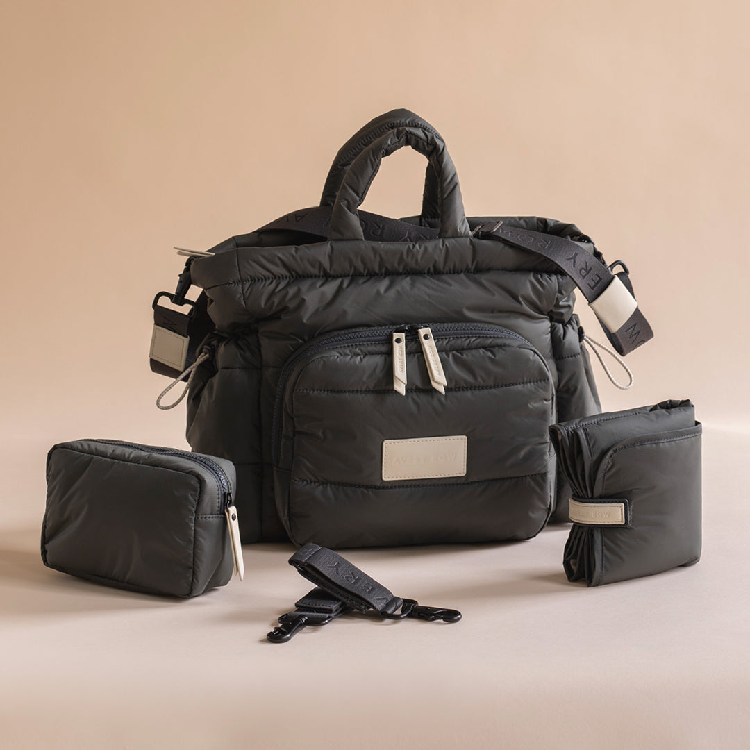 Black travel bag with accessories on a beige background