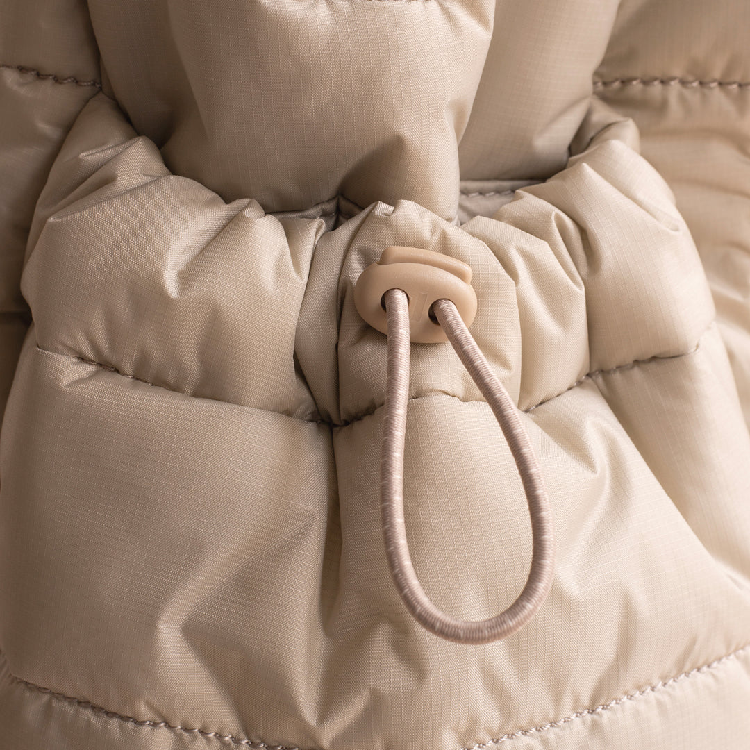 Close-up of a beige puffer jacket with a drawstring hood.